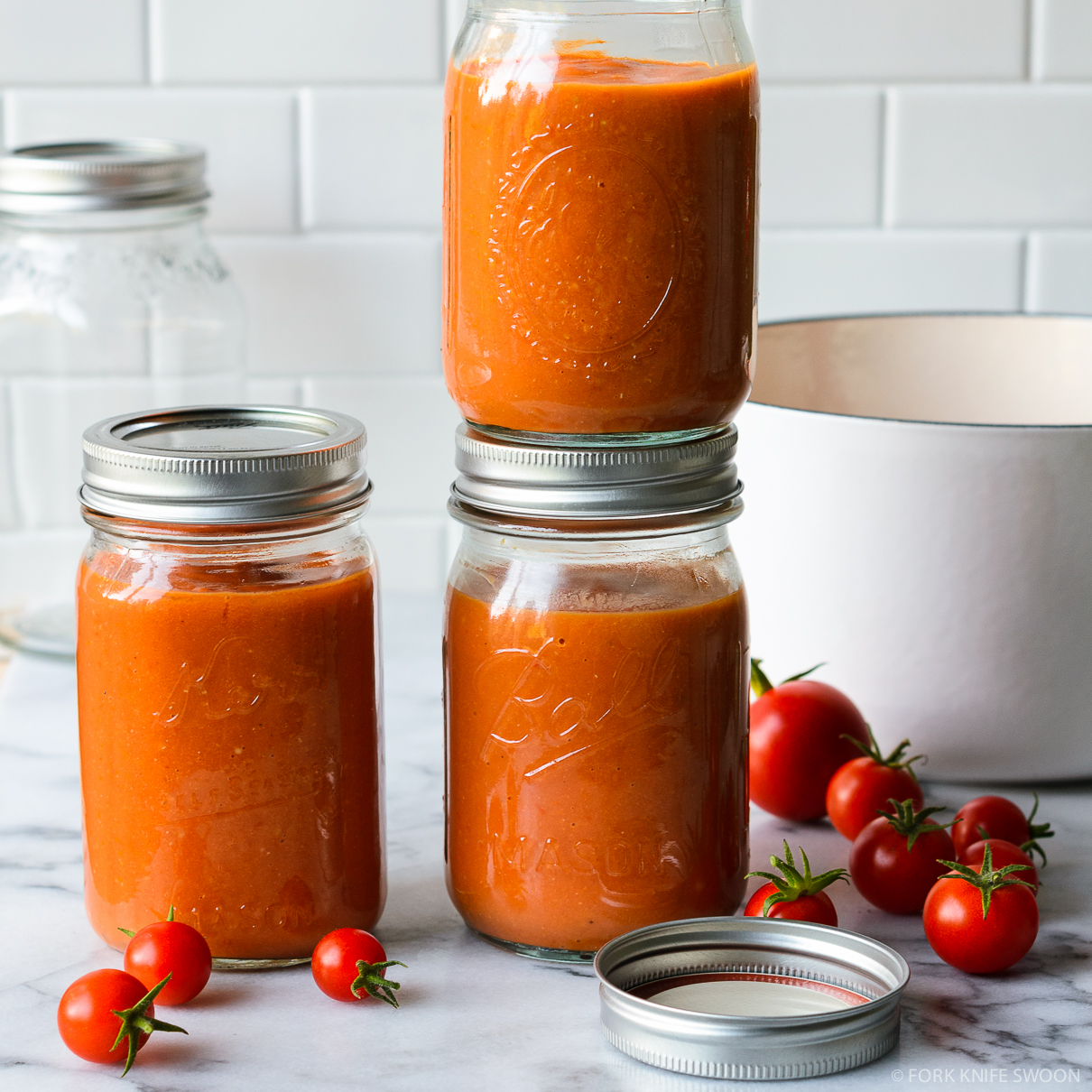 A bowl of keto tomato soup with a spoon and a pot of soup in the fridge