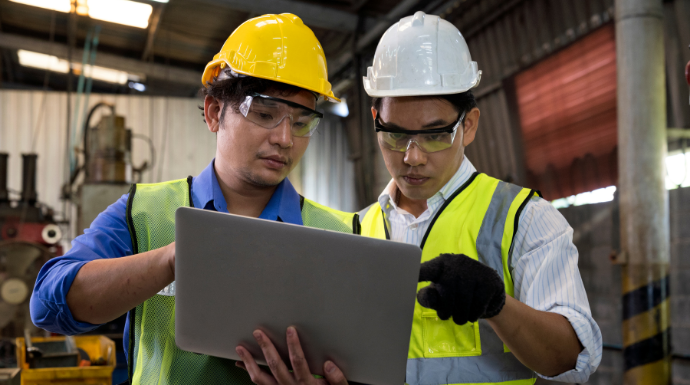 Manufacturing employees looking at a computer, potentially viewing real-time data to boost efficiency.