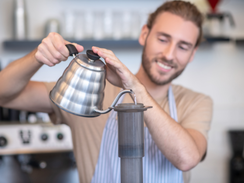 Barista despeja água no cilindro da AeroPress. Foto: stagestock - Canva