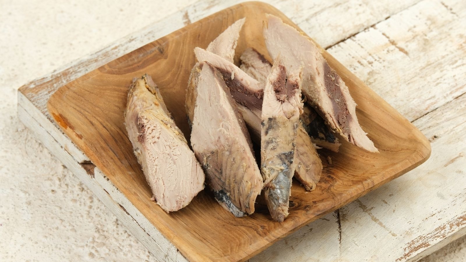 Cooked mackerel fillets on wooden plate showing flaky and tender fish texture