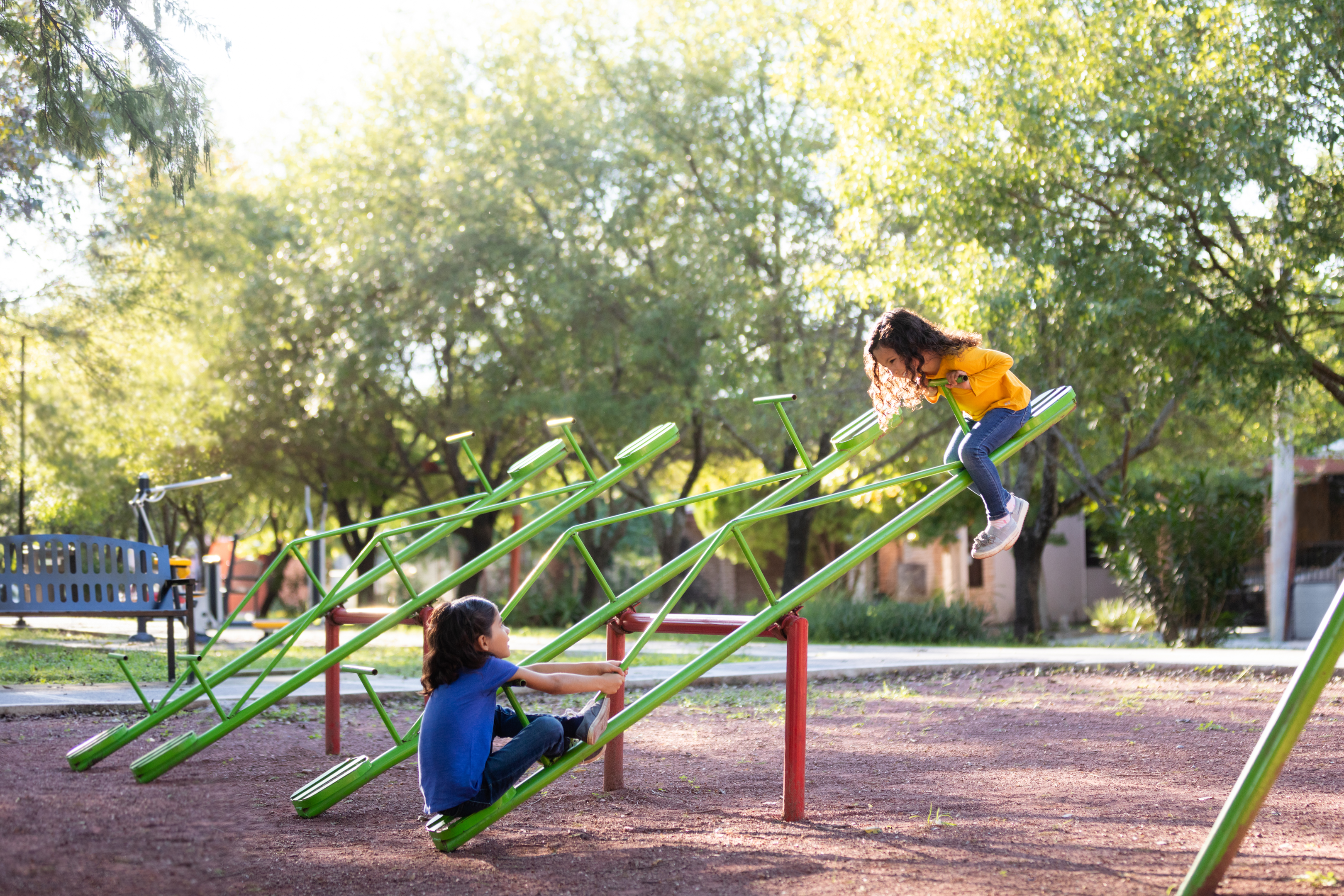 Two siblings playing on a seesaw at a park
