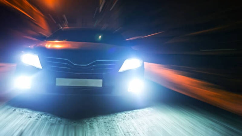 Bright LED headlights of car illuminating the road. 