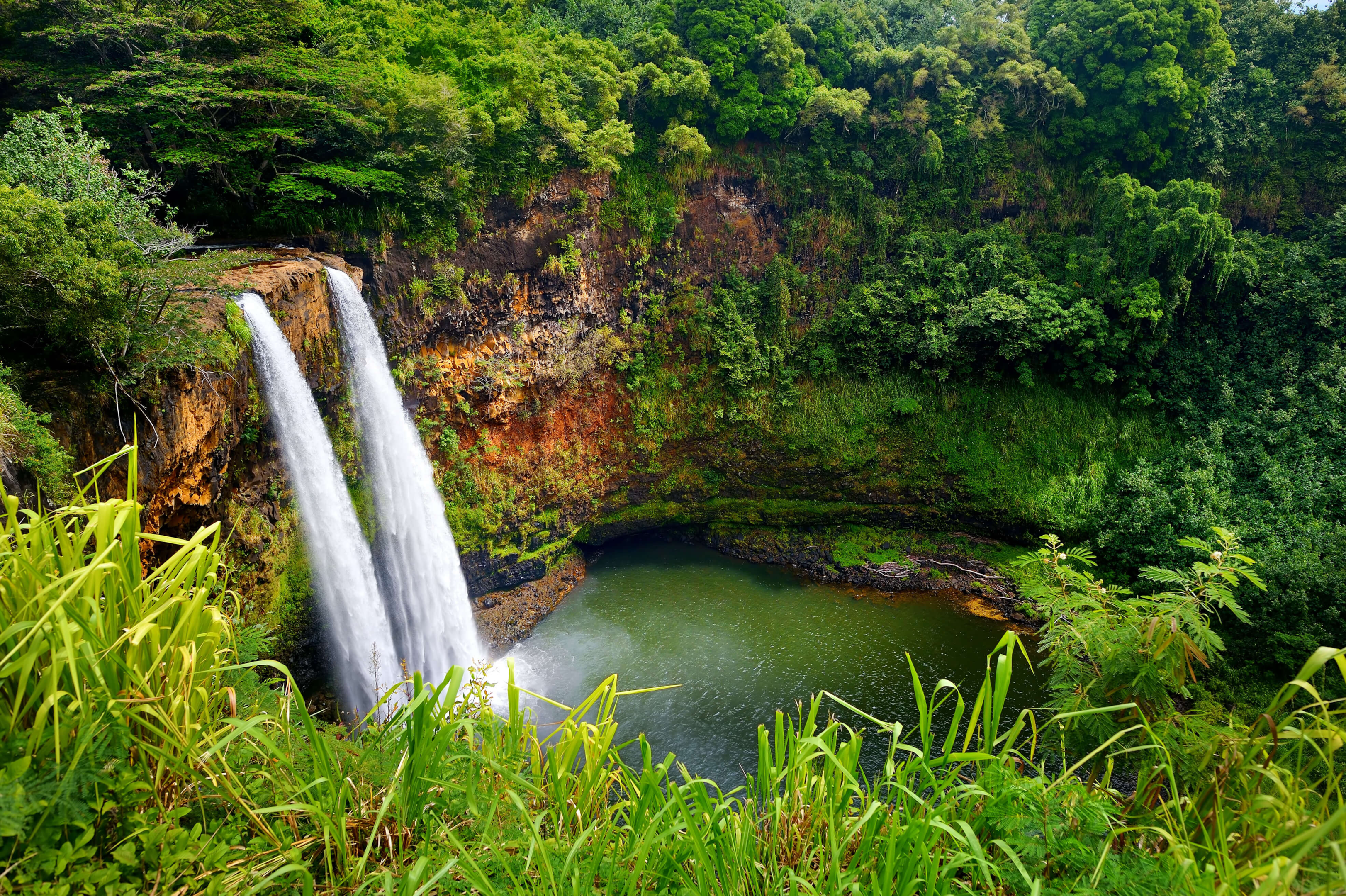 two waterfalls surrounded by trees and greenery