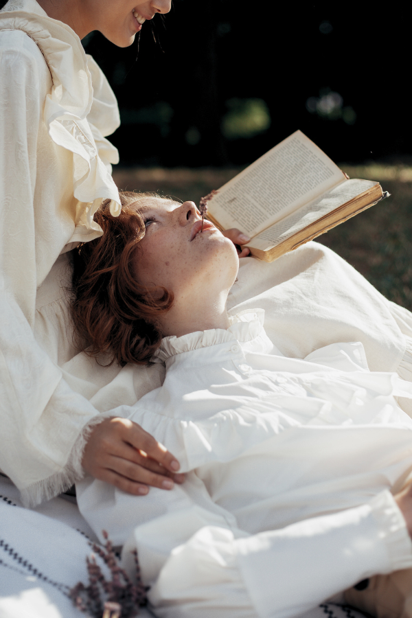 two women gaze at each other as one reads to her girlfriend or wife