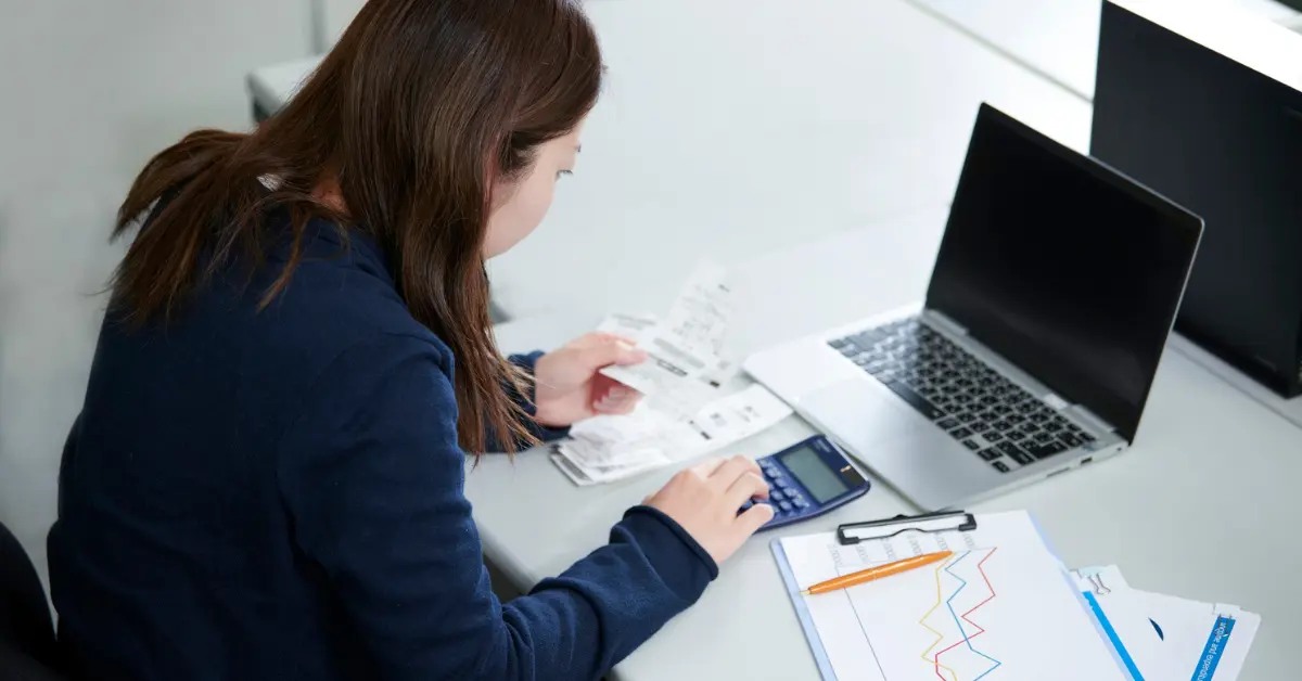 Woman reviewing receipts and calculator demonstrating how to compute mileage for tax deductions.