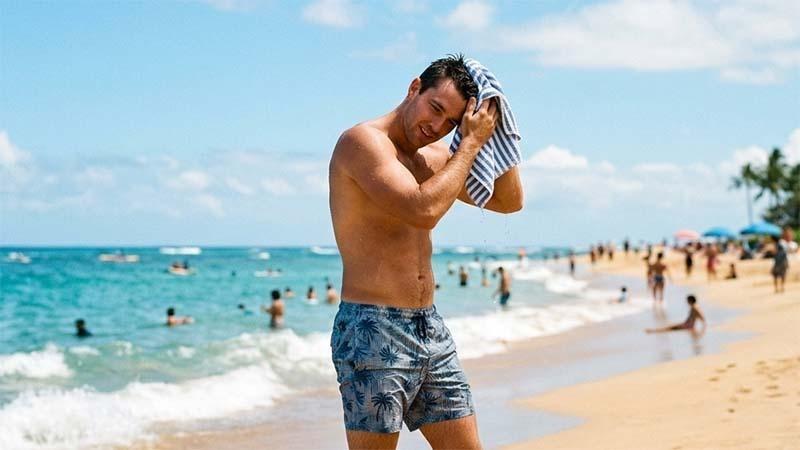 A man drying his hair on the beach
