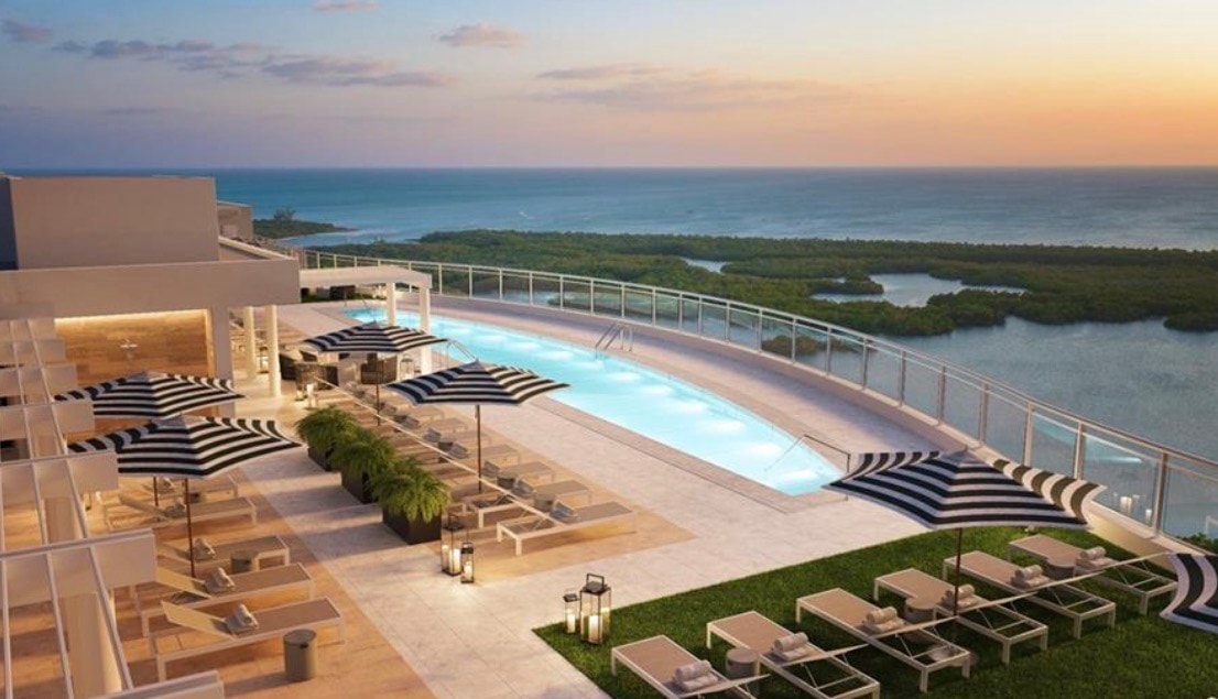 The image depicts a luxury condominium interior featuring floor-to-ceiling windows that provide breathtaking Gulf of Mexico views, complemented by modern coastal design elements. This sophisticated living space exemplifies the refined coastal luxury found in the prestigious Kalea Bay community, showcasing the essence of upscale Naples, FL living.