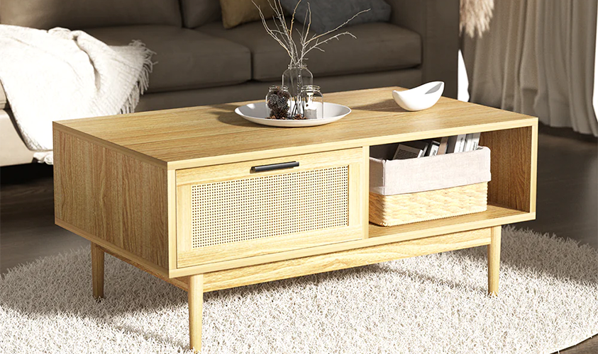 An Artiss Rattan coffee table with storage drawer, set in a neutral coloured living room on a shag rug. It has minimal decor including a straw and fabric storage basket, two ceramic dishes and a variety of dried plants in jars.