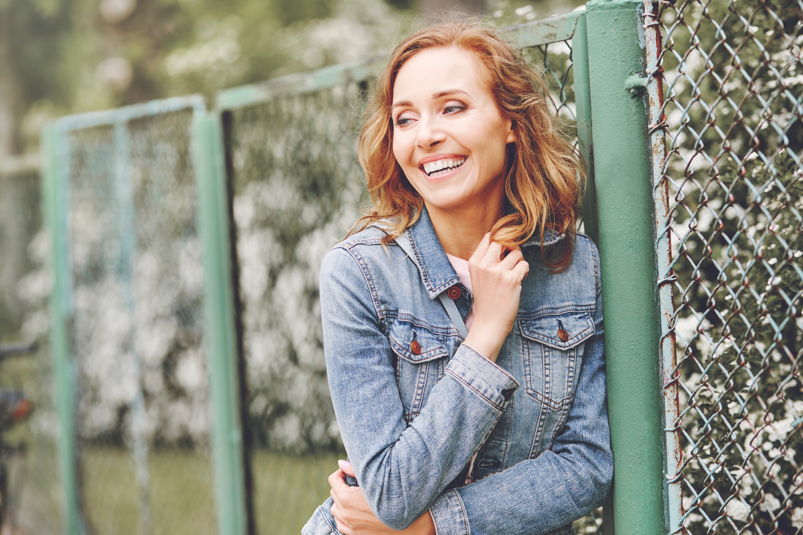 a smiling woman who went through the dental implant vs crown process and chose the best option for her personal needs
