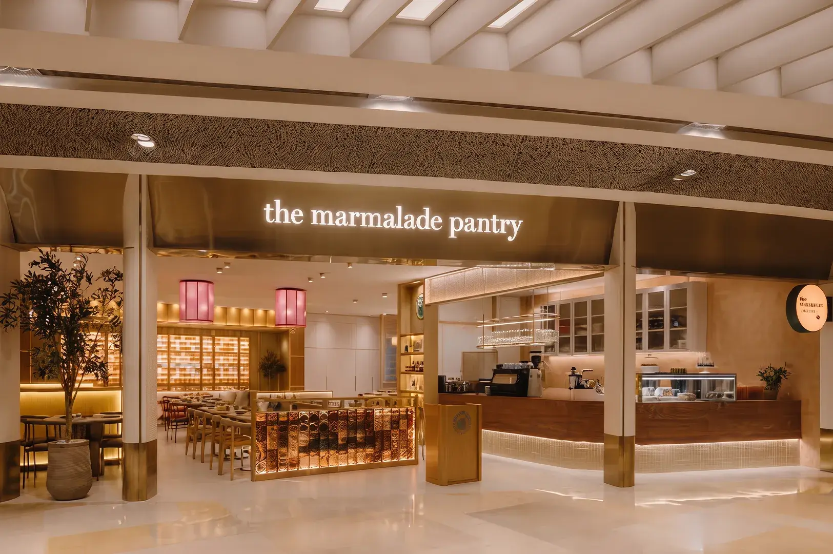 Illuminated modern storefront of The Marmalade Pantry with wood paneling and warm ambient lighting.