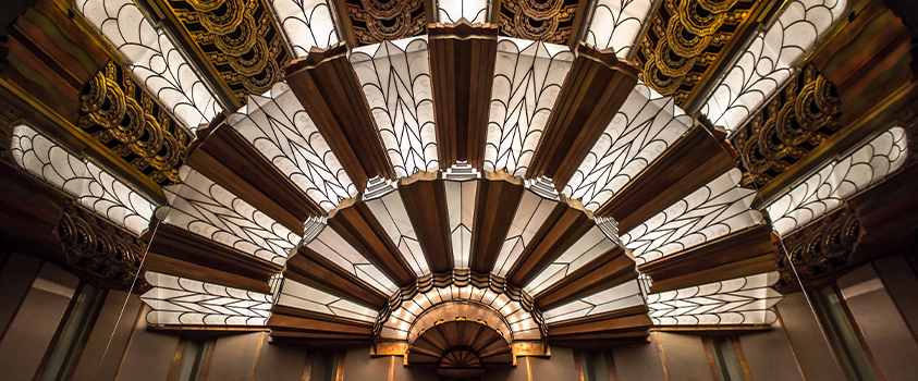 This stained glass and metal ceiling fans out with repeating geometric patterns, a testament to Art Deco style.