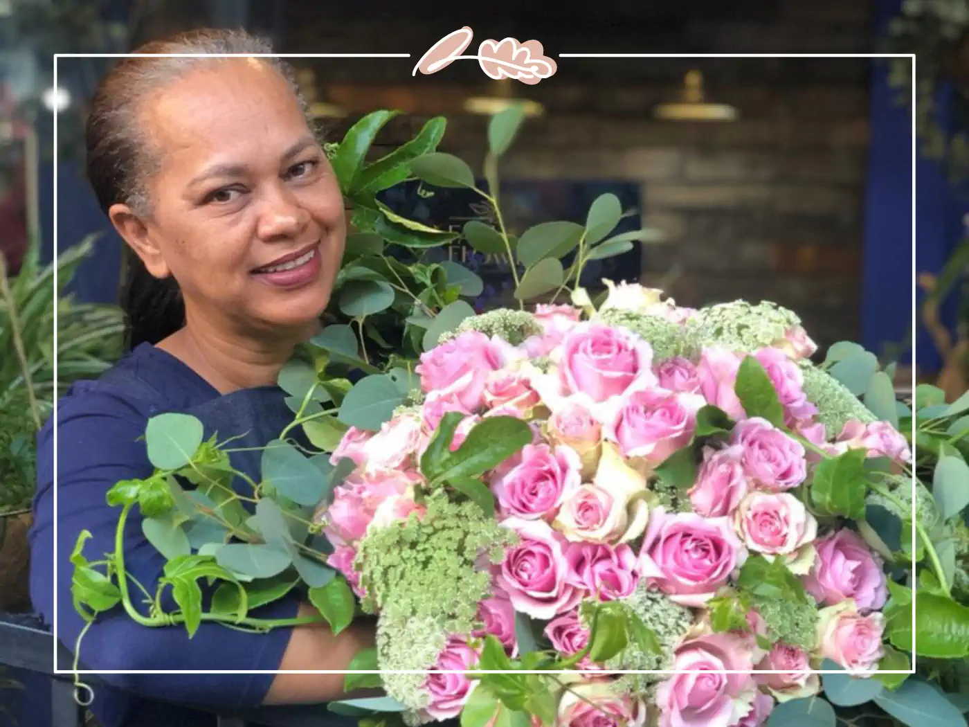 Woman smiling while holding a large bouquet of pink roses and greenery - fabulous flowers and gifts