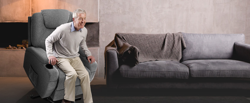 An elderly man uses the lift function to get out of an Artiss Grey Fabric Electric Lift Motor Recliner. 