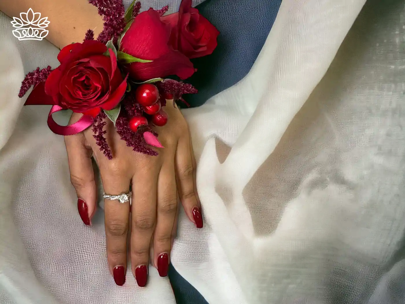 A close-up of a hand adorned with vibrant red nail polish and a sparkling engagement ring, gracefully holding a stunning arrangement of deep red roses and lush, textured accents, symbolizing elegance and celebration. Fabulous Flowers and Gifts - Matric Dance. Delivered with Heart.