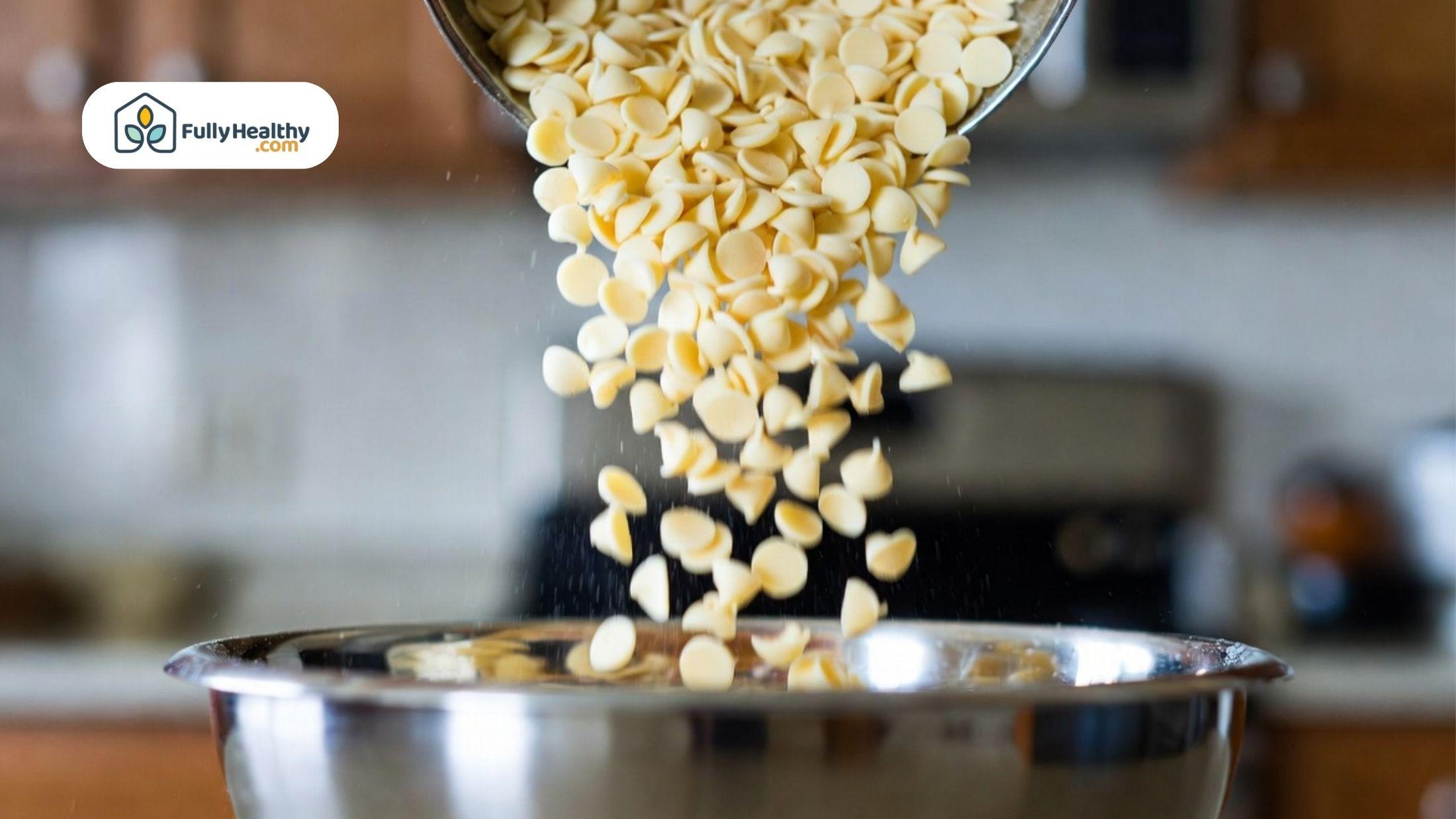 White chocolate chips pouring into a bowl during baking preparation.