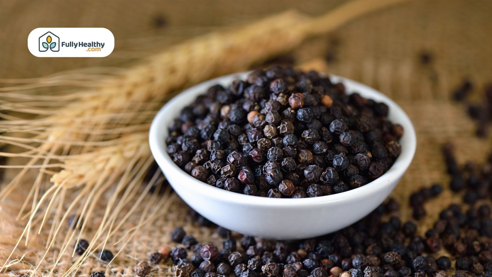Whole black peppercorns in white bowl with rustic background setting
