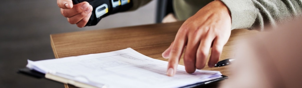 Employee with hand injuries reviews forms to complete workers' compensation claim.
