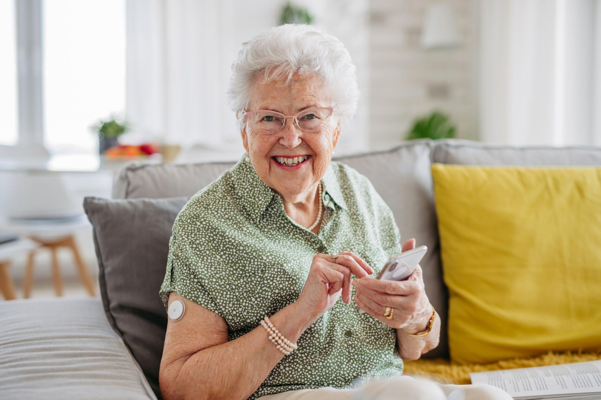 A happy woman proudly displaying her CGM device, a modern tool to maintain blood glucose and effectively control blood glucose levels.