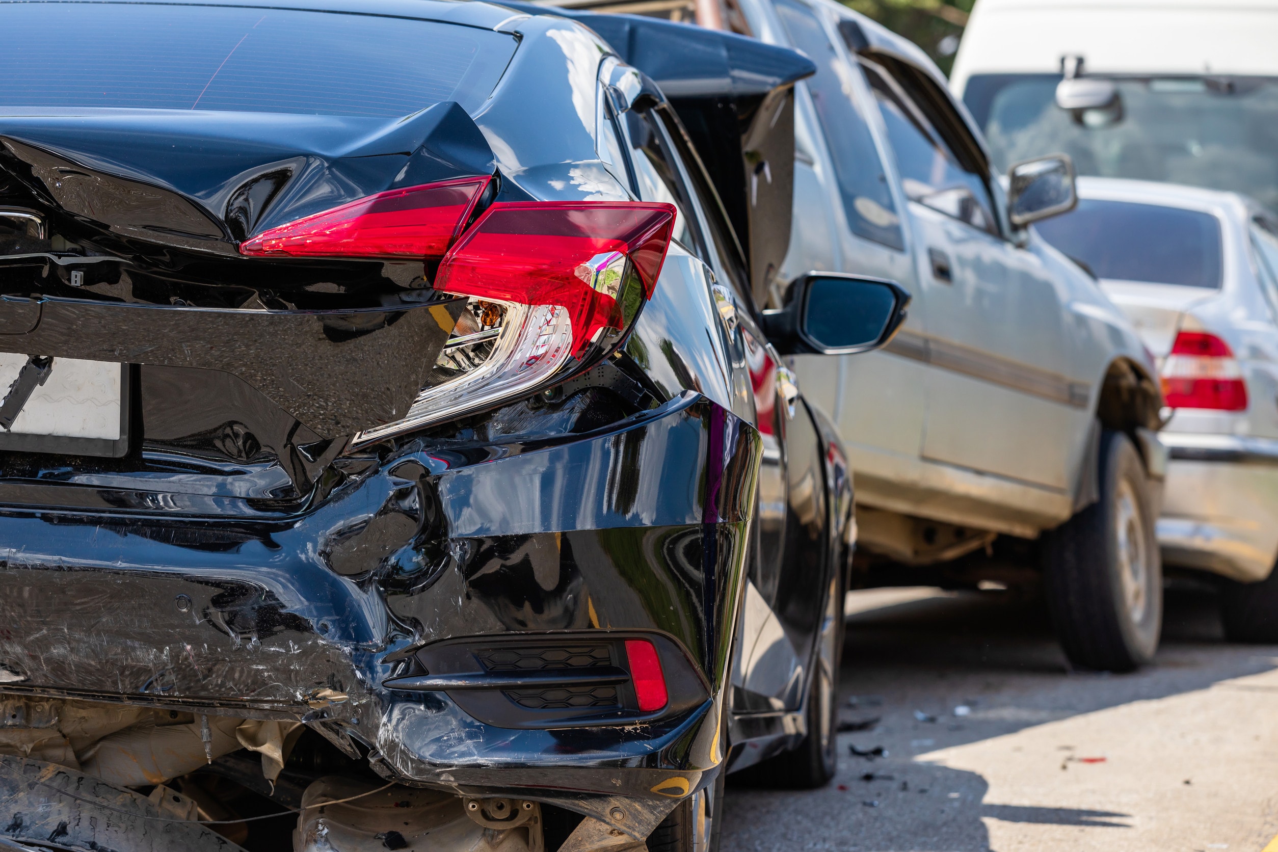 A black car crashes into the read end of the car in front