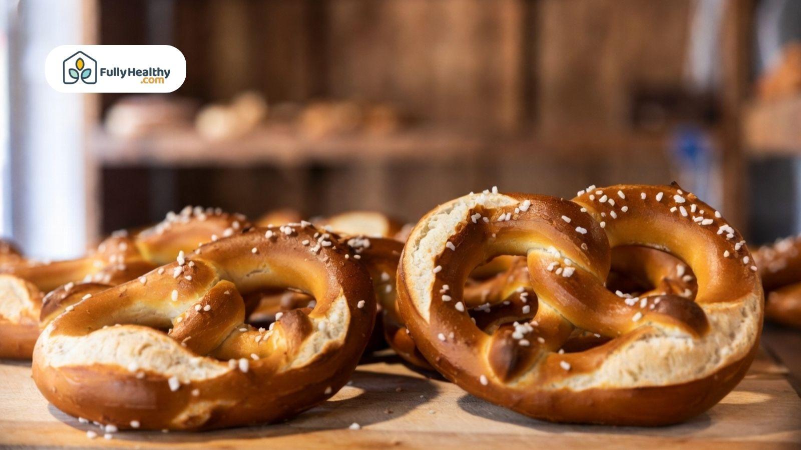 Freshly baked traditional soft pretzels on rustic bakery counter with coarse salt.