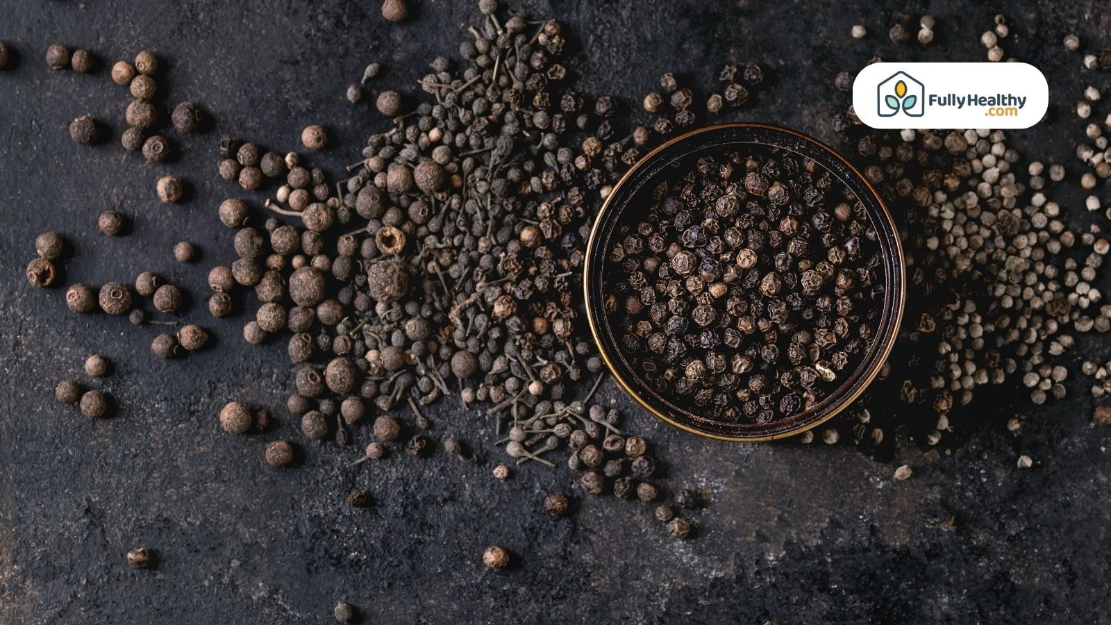 Assorted peppercorns scattered with bowl on dark textured background