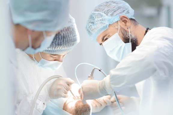 oral surgeons in operating room performing open joint surgery