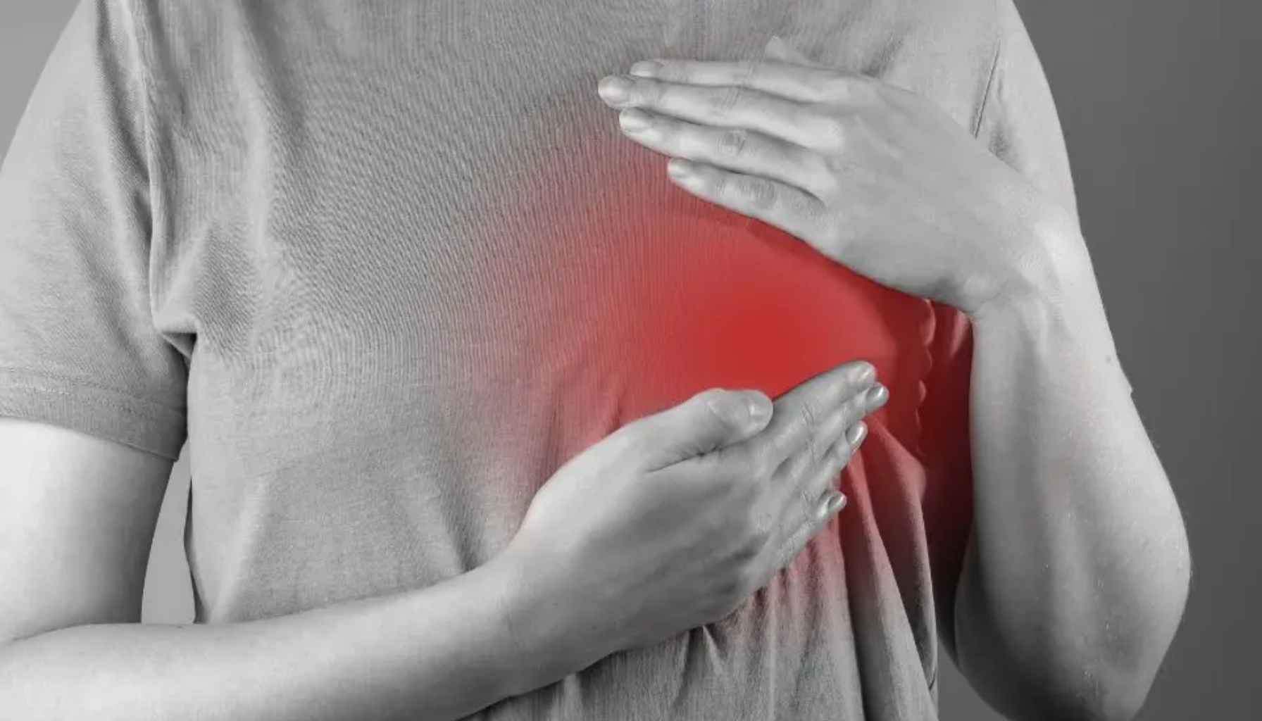 Kvinne holder hånden på brystet med rød markering som symboliserer smerte eller ubehag.