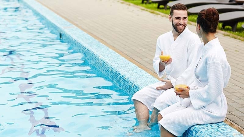 A couple by the pool in bathrobes