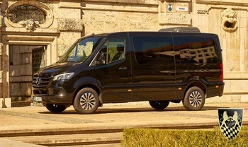 A tour bus travels through the picturesque Bavarian countryside, showcasing rolling hills and lush landscapes, as it heads towards the enchanting Neuschwanstein Castle. This scenic journey is part of a day tour from Munich, offering travelers a glimpse of the beautiful terrain that surrounds the legendary castle grounds.