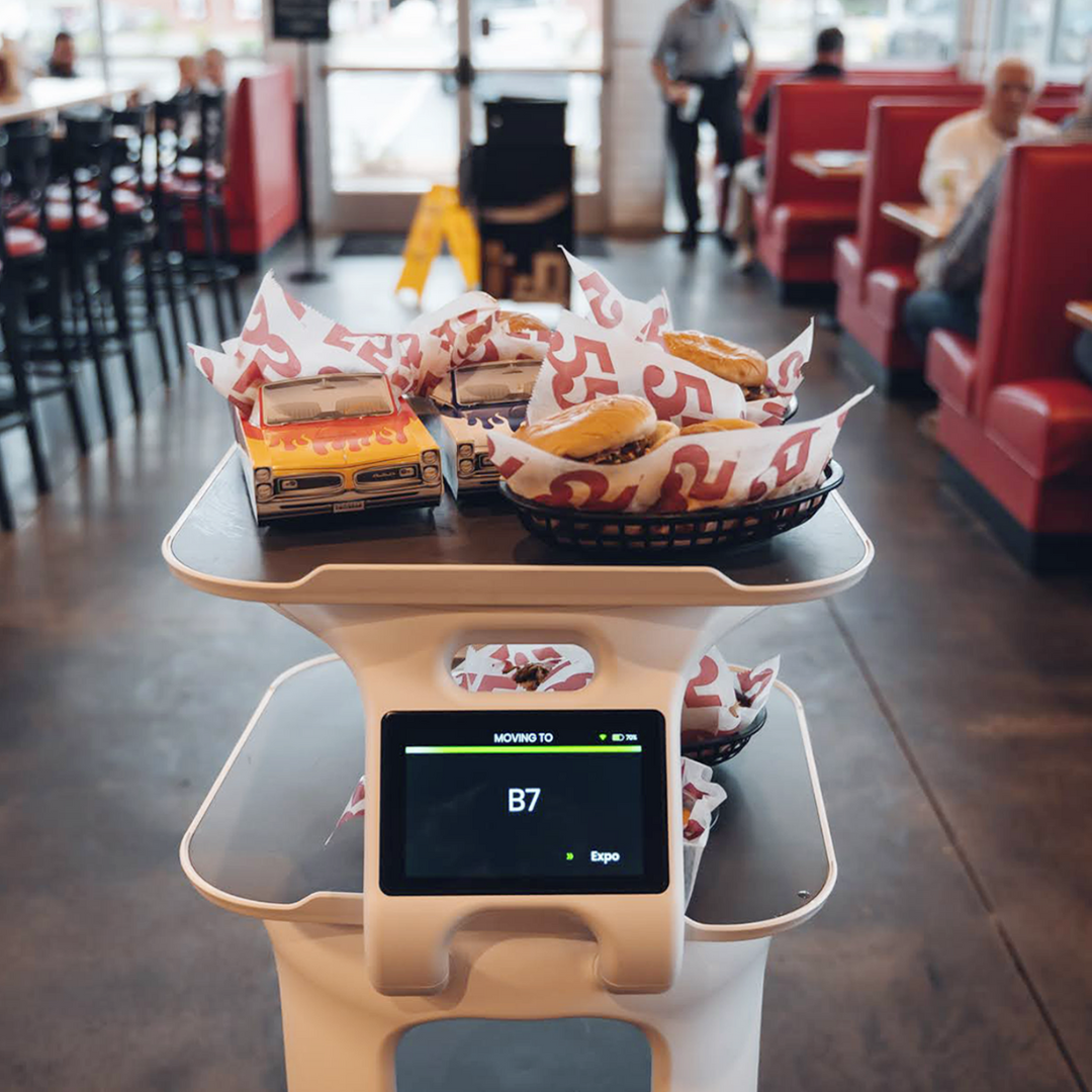 Servi service robot delivering burgers to a table, ranked better than the Pepper robot from softbank from the latest news.