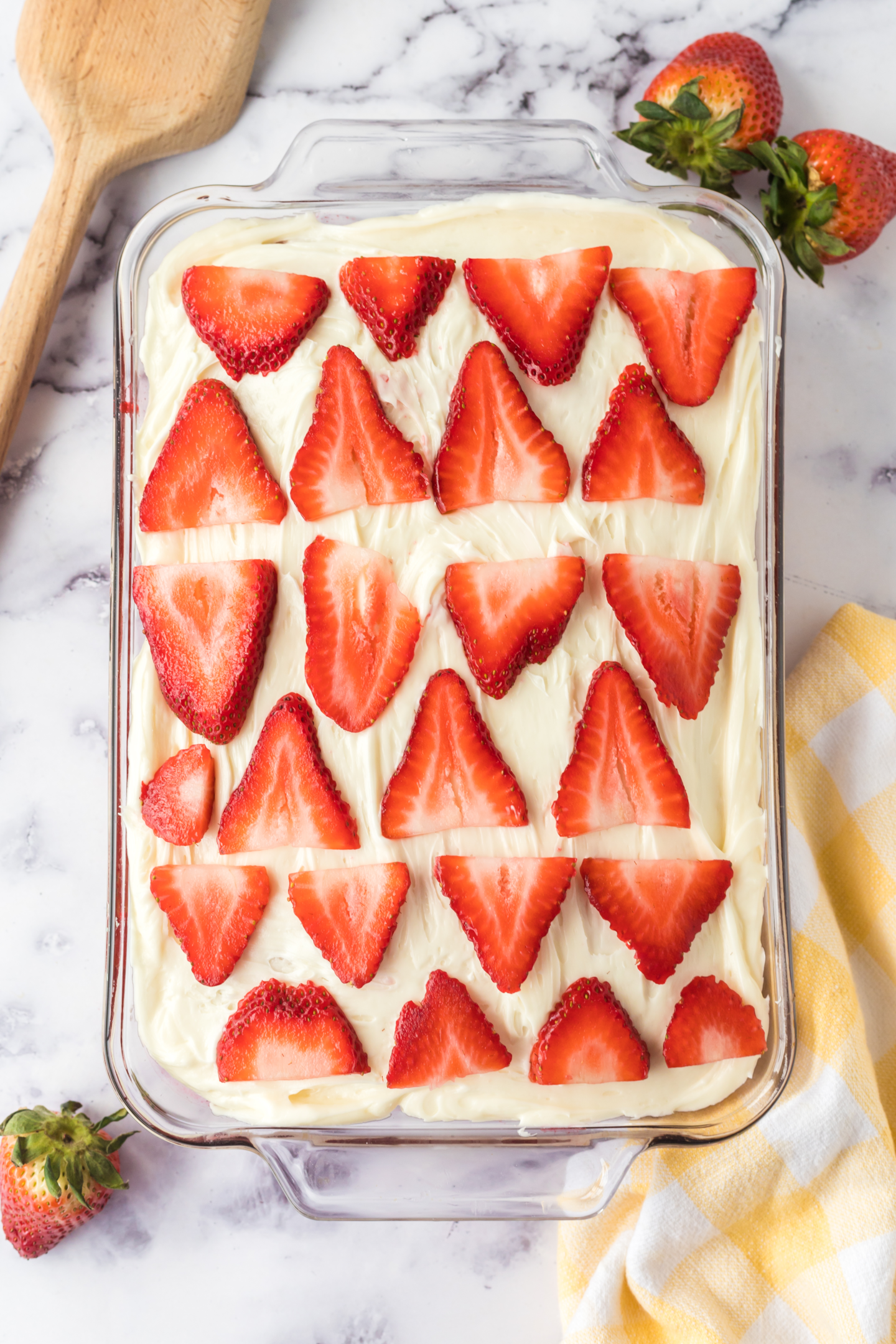 frosted cake in pan topped with sliced strawberries in prepared pan