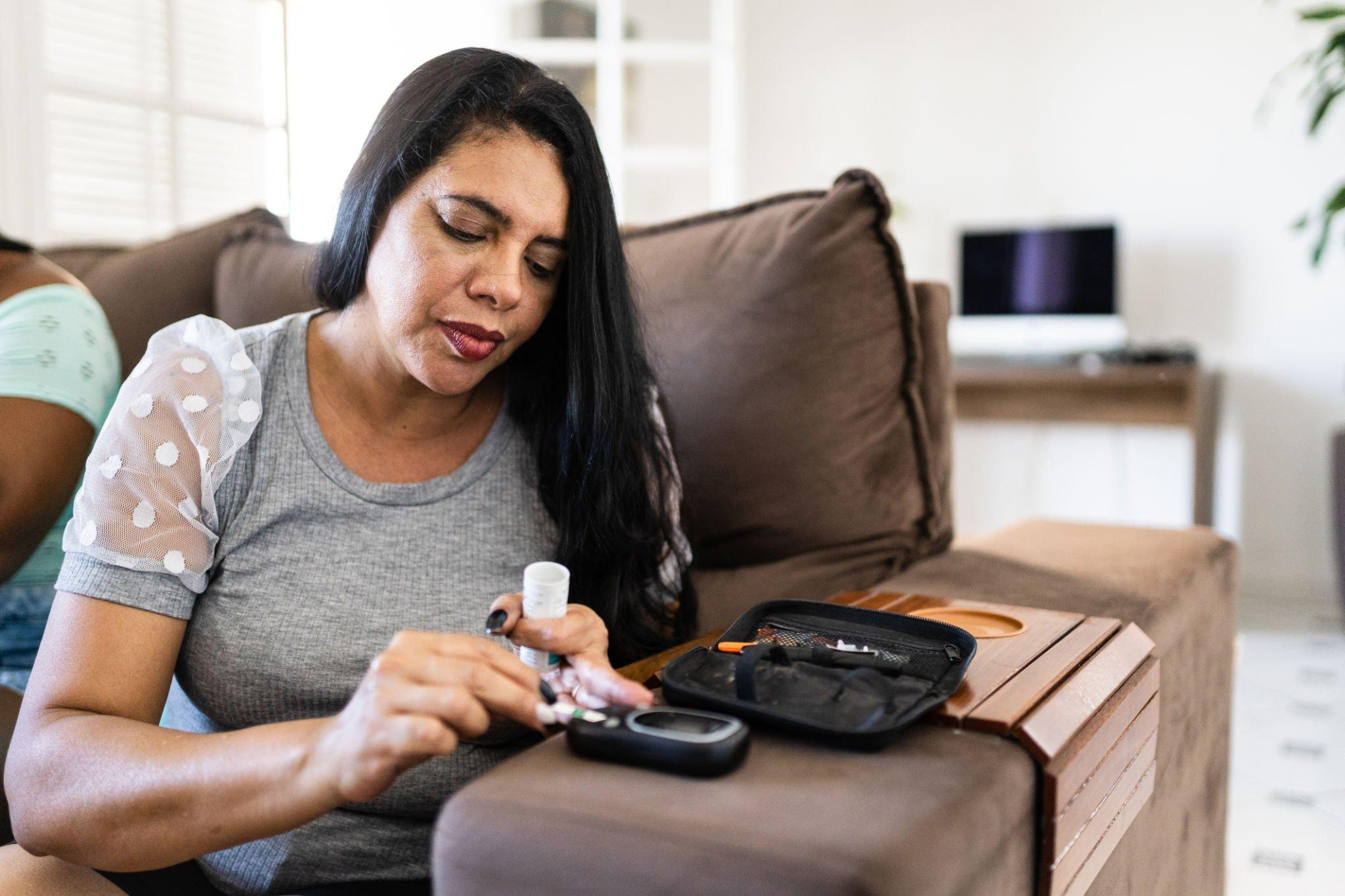 A person checking their blood sugar levels using a glucose meter. Monitoring average glucose, urgent low glucose