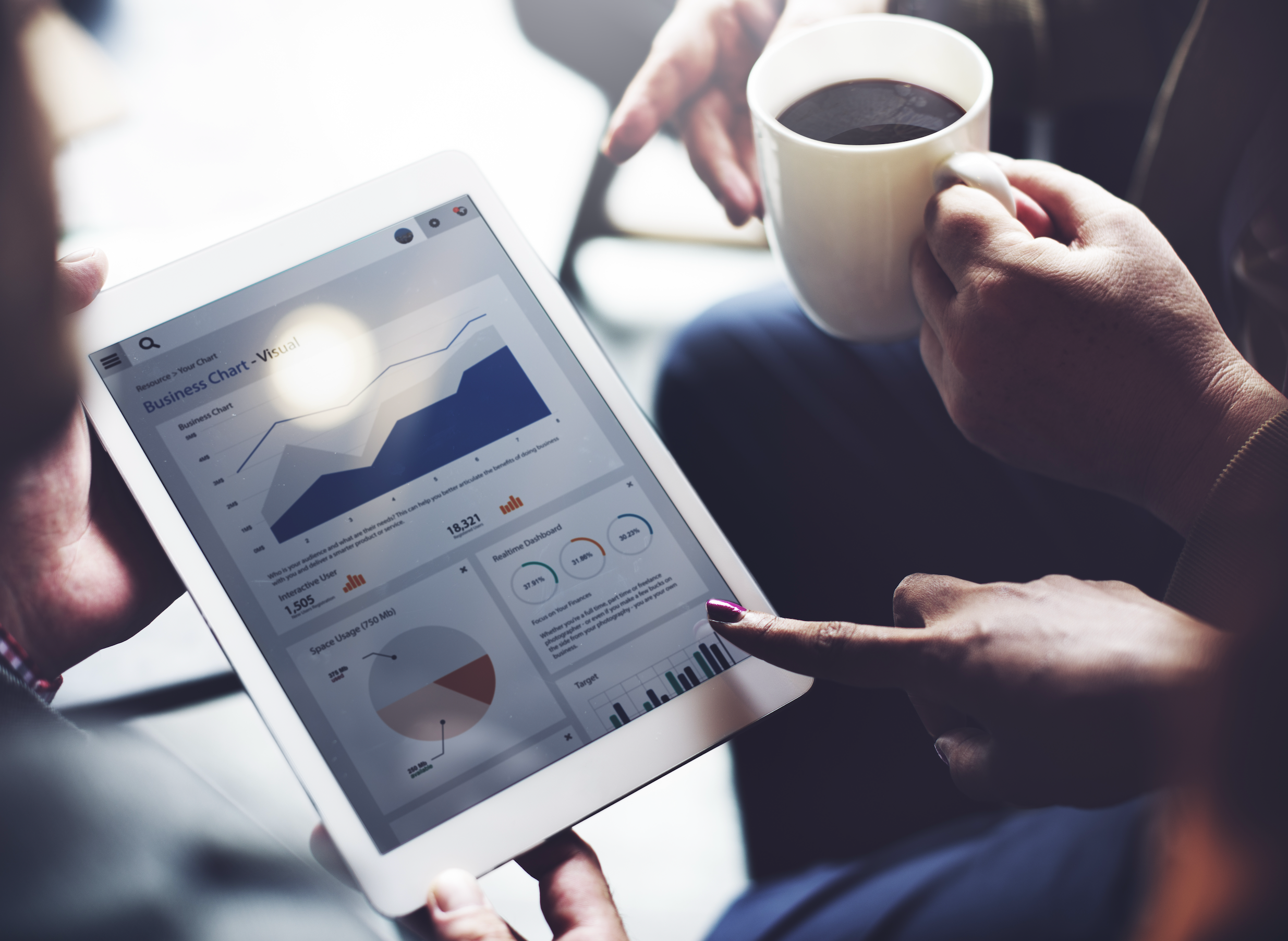 three people sit around a tablet showing marketing performance statistics against a light background