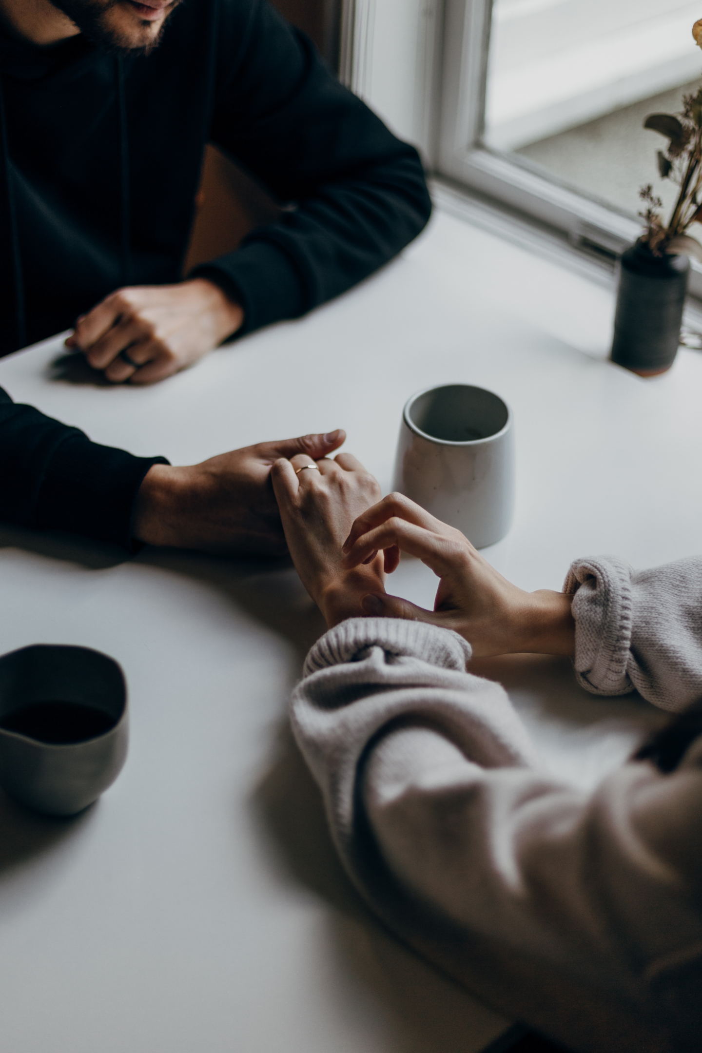 two people sitting together holding hands with coffee