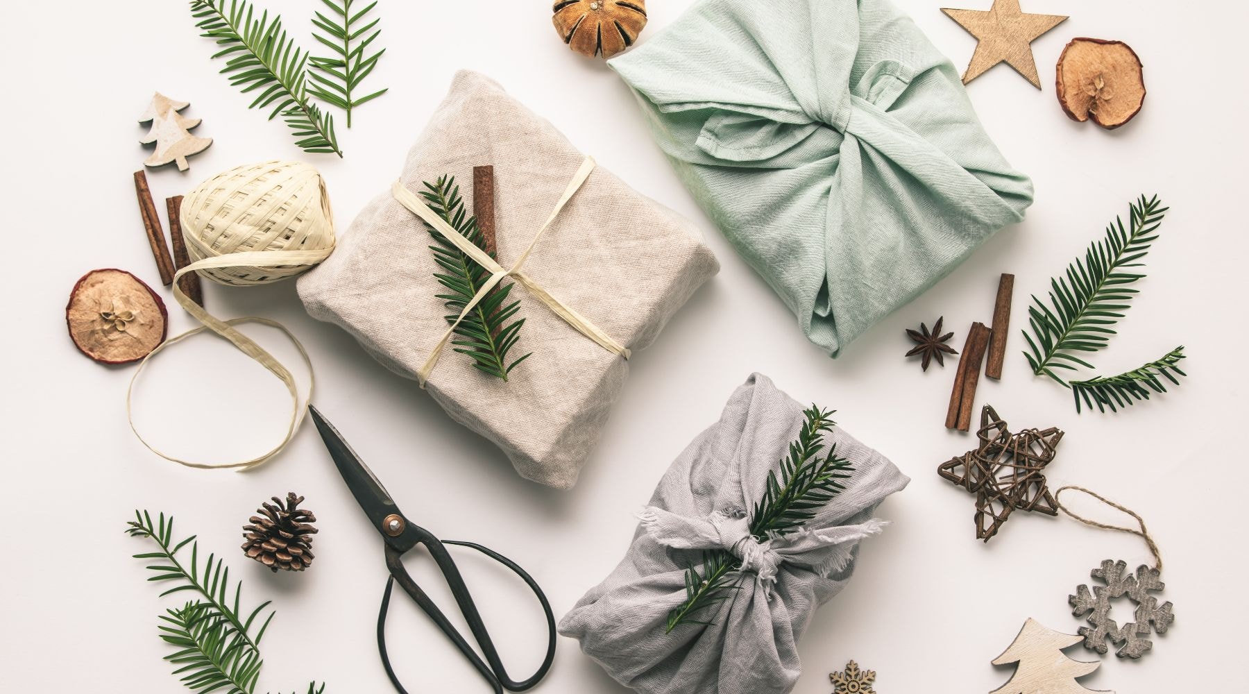 Flat lay of eco-friendly gift wrapping materials including dried orange slices, pine cones, and recycled paper.