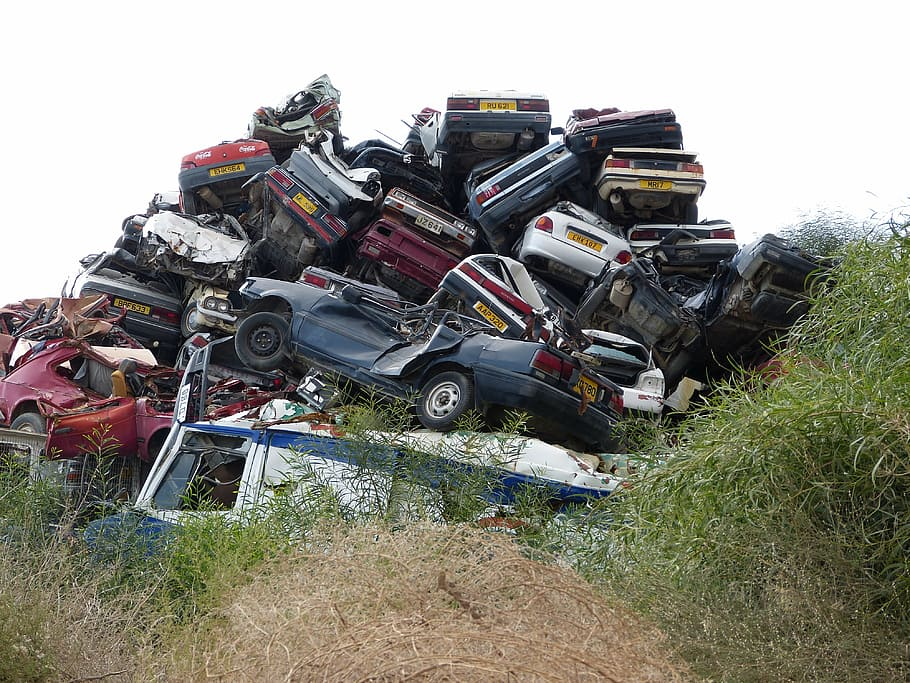 A man looking at a pile of junk cars