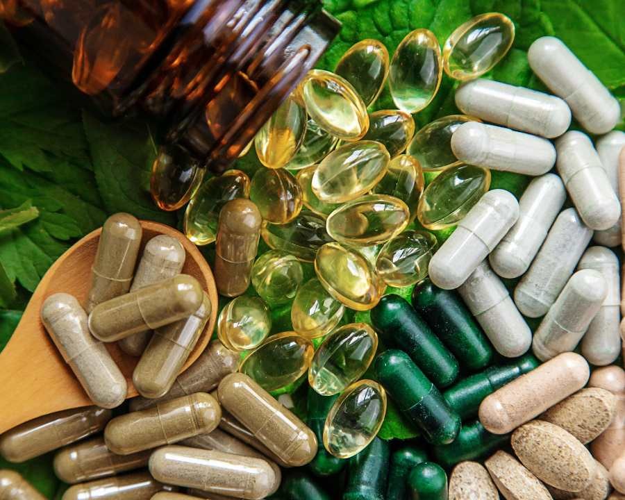 Close-up of various health supplements spilling from bottle and spoon – natural nutrition support from The Good Stuff