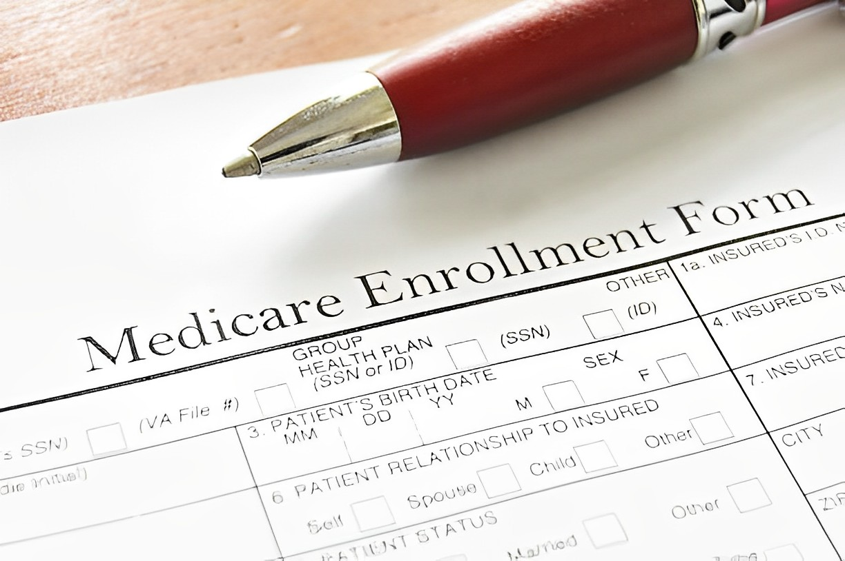 A photo of a Medicare Enrollment Form with a ball pen above it 