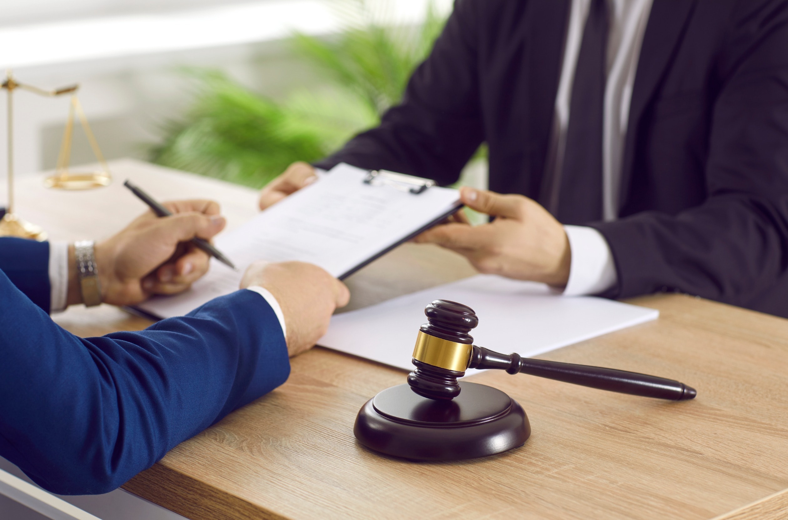 A personal injury solicitor asks a client to sign a paper on a clipboard