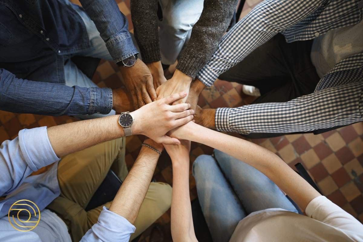 Close-up of team members placing their hands together in a group cheer, symbolising unity, trust, and a shared commitment to their goals.