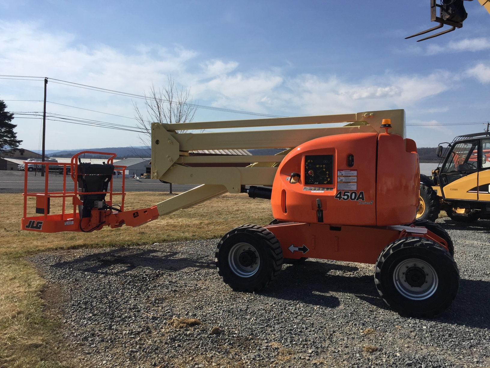 A small orange lift truck parked on a gravel lot, ready for use