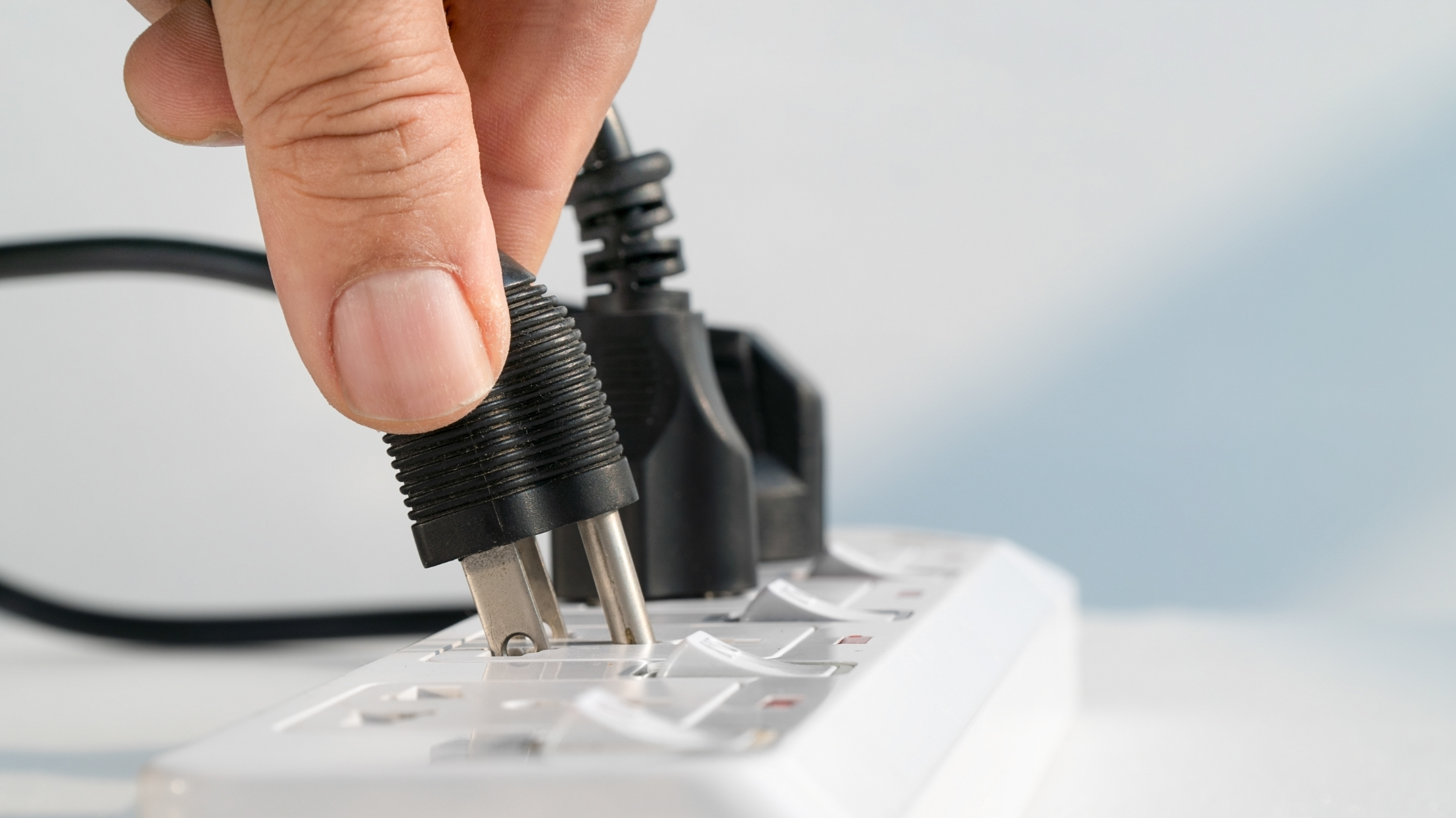 Hand unplugging a power cord, symbolizing the removal of unused telecommunications services from enterprise businesses.