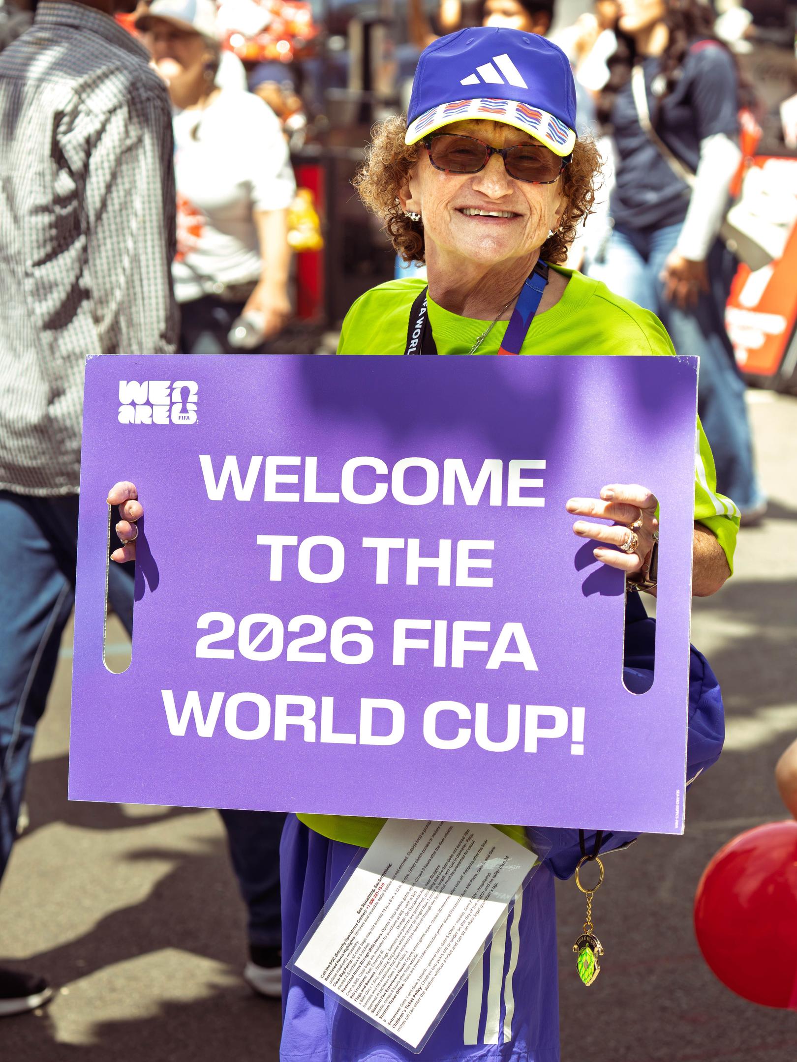 Photo of a 2026 FIFA World Cup volunteer holding a sign that says welcome to the 2026 FIFA World Cup