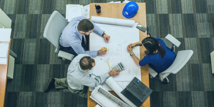 3 employees sitting at a table and working on a business plan.