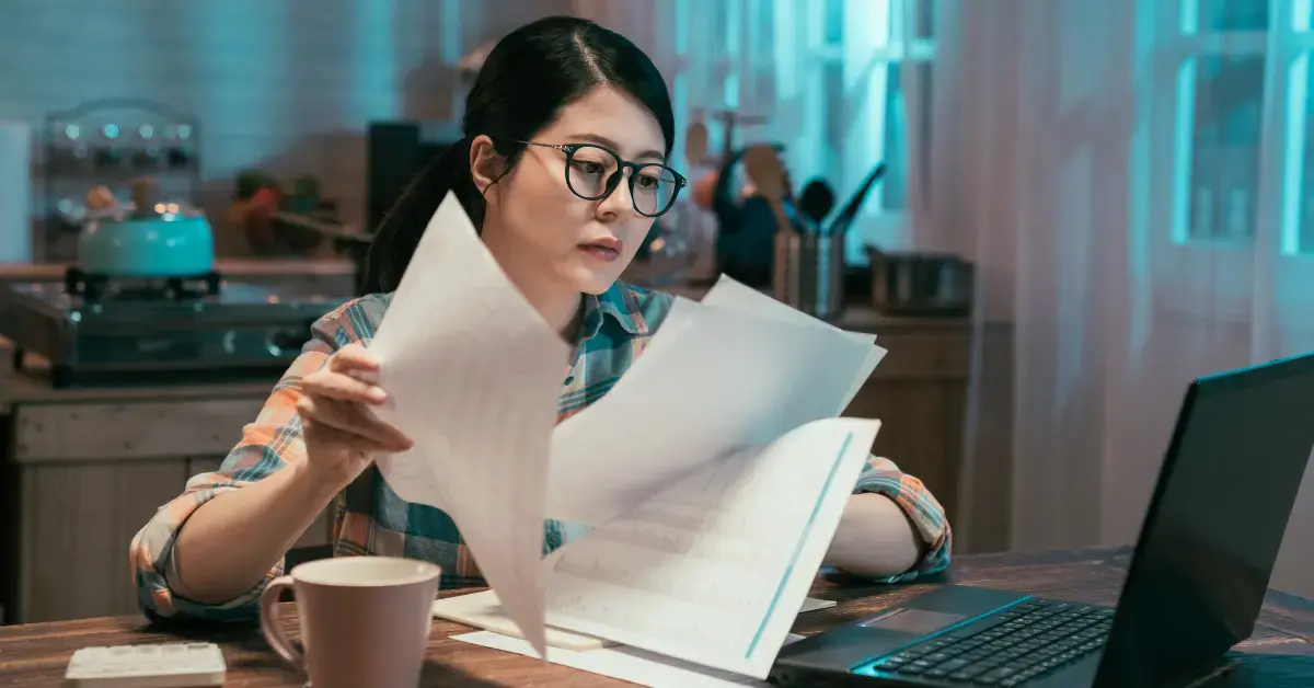 Woman reviewing a rejected Offer in Compromise and preparing a Form 13711 appeal with tax documents.