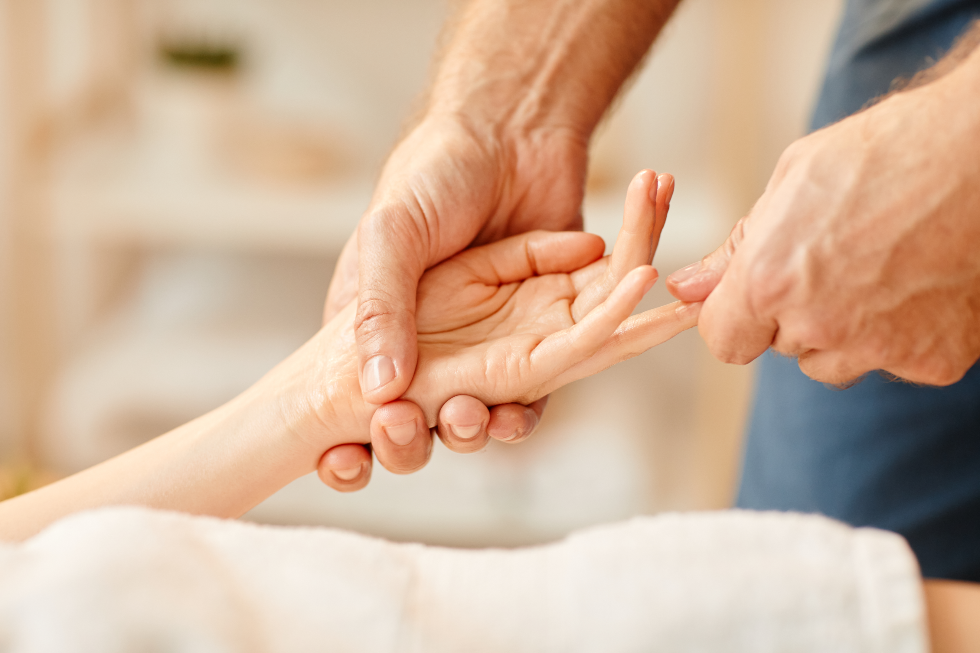 An olderly practitioner is treating a hand. 