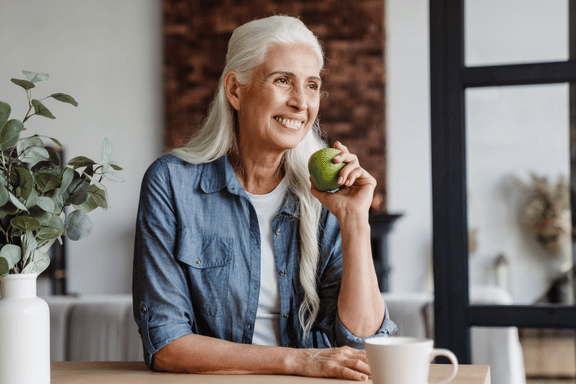 woman with implant dentures getting ready to bite into an apple