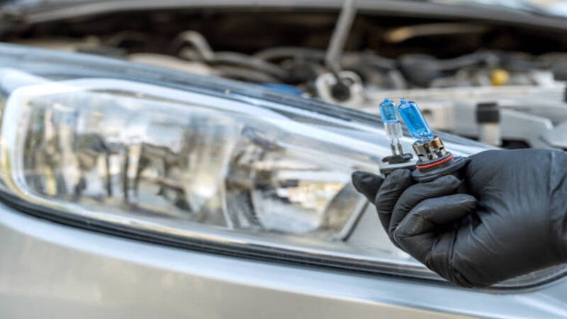 A professional installing aftermarket LED headlights in a car. 