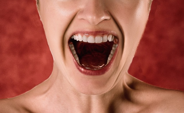 A cropped image of a woman with open mouth, screaming or shouting. 