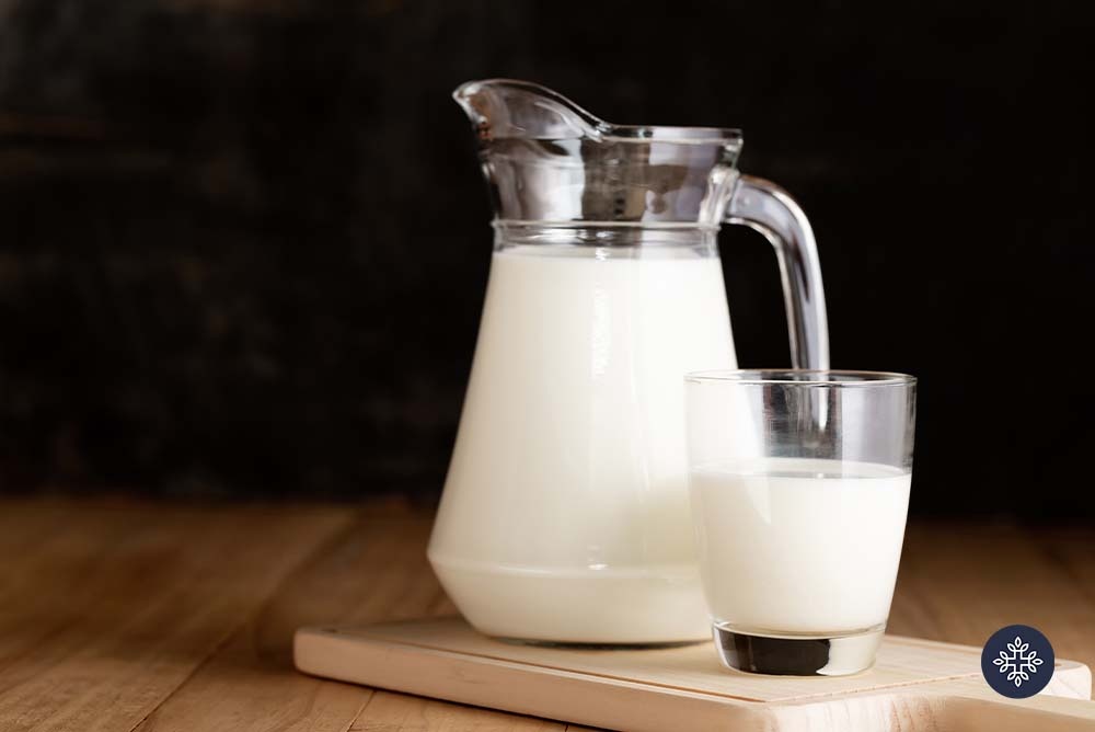 Nictoinamida ribósido que se encuentra en los alimentos. Vaso de leche junto a una jarra de leche de cristal.